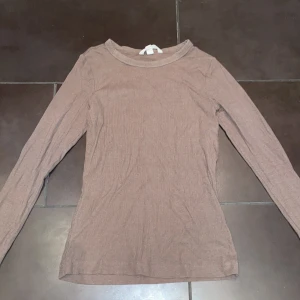 Brun långärmad tröja från H&M - En basic brun långärmad tröja från H&M i mjuk bomull. Tröjan har rund halsringning. Den sitter bra på och är i en jättefin höstig färg.