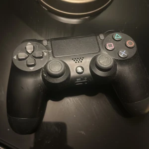 PlayStation 4 DualShock 4 Controller - Original Sony DualShock 4 trådlös handkontroll till PlayStation 4. Kontrollen är svart och visar tecken på normalt slitage, men alla knappar och spakar ser hela ut. Perfekt för extra spelare eller som ersättare.