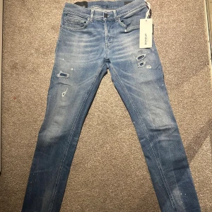 Dondup George jeans - Säljer ett riktigt eftertraktade Dondup George jeans i väldigt eftertraktad blå tvätt med slitningar och små färgstänk för en cool, trendig look. Jeansen har fem fickor, knappgylf och är tillverkade i mjukt jeanstyg. Made in Italy och riktigt snygga detaljer. OBS!!! Jeansen är aldrig använda och helt nya kvitto medföljer vid köp!!! Köpta på Zgander i ödåkra Nypris 3795kr mitt pris endast 1199kr mer än 70% rabbat. Skynda fyna dessa otroligt eftertraktade och sjukt snygga jeans!