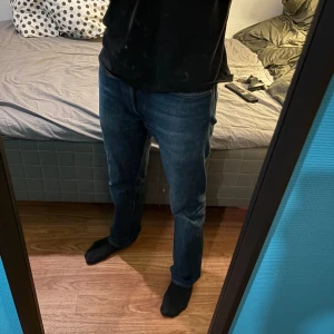 Levi's 501 blå jeans W30 L32 - Klassiska Levi's 501 jeans i mörkblå tvätt med raka ben och normal passform. Jeansen har fem fickor, knappgylf och snygga kontrastsömmar. Perfekt för dig som gillar tidlös stil och vill ha ett par jeans som funkar till allt.
