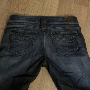 Mörkblå Lee jeans med bootcut - Snygga mörkblå lågmidjade jeans från Lee med bootcut passform. Svinsnygga!!! Midjemått: 44cm innerbenslängd: 74cm gylflängden: 20 cm😍💌LÖP O KÖP! Perfekt till hösten!! Passar storlek L/M se mått ovan. Storlek W33 L33 på lappen men de är ganska små i storleken enligt mig. Ganska strechiga material och sköna på. As snygga och perfekta jeans!! 