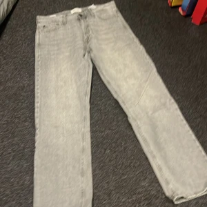 Grå jeans Jack & Jones Relaxed Chris - Säljer ett par grå jeans från Jack & Jones, modellen Relaxed Chris. De har en avslappnad passform med raka ben och klassisk femficksdesign. Jeansen är tillverkade i bomull och har en ljusgrå tvätt som ger en cool vibe.