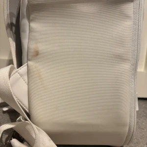 Douchebag  - Snygg och stilren vit ryggsäck från Db med flera smarta fack, justerbara remmar och robusta spännen i metall. Väskan har en modern, boxig form och är tillverkad i slitstarkt syntetmaterial. Perfekt för dig som vill ha en clean och praktisk look.                                                                                           Backpack PRO White Edition 