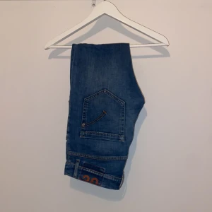 Blå slim fit jeans från dundup  - Snygga blå jeans från Dundup i model mius. Som ni ser på bild 3 är dem sönder vid låret men lagade, inget som märks när du har på dig dem men ändå en stor defekt, därför det billiga priset! Passar en grabb mellan 165-170