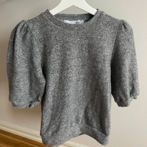 Grå puffärm tröja  - Supermjuk grå tröja från lager 157 med puffärmar och rund halsringning. Tröjan har en enkel, stilren look och är gjord i ett mjukt material som känns skönt mot huden. Perfekt för dig som gillar en chill men ändå trendig vibe.