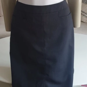 Kjol * stl 34 * Woman by SIR of Sweden - Så snygg kjol.  * Nyskick, använd endast EN gång  * Märke: Woman by SIR of Sweden  * Stl 34  * Svartgrå med struktur.  * Virgin wool.  * Mått, mätt rakt över:  -Midja ca 35 cm.  -Stuss ca 46 cm.  -Längd ca 59 cm.  * Två diskreta fickor fram.  * Nypris ca 2000 kr.   Djur och rökfritt hem. Se bilder och förstora då de ingår i beskrivningen.  Se gärna mina övriga annonser. 