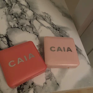 CAIA rouge duo i rosa och persika - Två CAIA rouge i snygga fyrkantiga dosor med spegel. Ena är ljusrosa med en djupare hallonfärg, den andra är korallfärgad med en persikoton. Båda är puderrouge och perfekta för att ge kinderna en fräsch färg. Säljes tillsammans! Köpte båda för 600 men säljer för 300 kr så hälften 