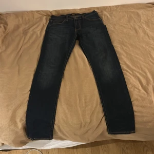 Mörkblå skinny jeans från Lee - Säljer ett par mörkblå skinny jeans från Lee med klassiska kontrastsömmar och femficksdesign. Jeansen har en tight passform och är tillverkade i stretchigt denimtyg för extra komfort. Perfekta för dig som gillar en smal siluett och stilren look.