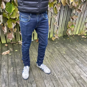 Mörkblå Replay Anbass jeans slim fit - Snygga mörkblå lee jeans med slimfit i modell Luke. Modellen är ca 180
