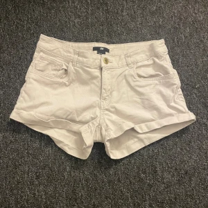Beige shorts från H&M, strl 36 - Snygga beige shorts från H&M i klassisk femficksmodell med uppvikta ben. De har normal passform, midwaist och är gjorda i mjuk bomull. Perfekta för varma dagar och enkla att matcha med din favorit-topp.