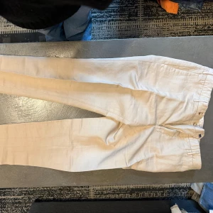 Beige slim fit chinos, storlek 30 - Snygga beige chinos i slim fit-modell med klassisk knapp och dragkedja framtill. Byxorna har en stilren look och är tillverkade i ett mjukt bomullsmaterial. Passar dig som gillar smalare siluett och ljusa färger.