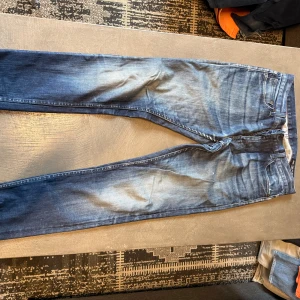 Crocker Super Skinny jeans blå 31/32 - Snygga blå jeans från Crocker i modellen 301 Super Skinny. De har en smal passform, klassisk femficksdesign och coola slitningar framtill och baktill. Jeansen är tillverkade i stretchigt denim för extra komfort och har en mörkblå tvätt med ljusare partier.