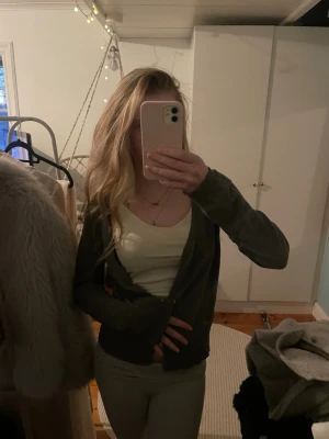 Grå kofta med ribbade muddar - Mysig grå kofta från H&M i mjukt material. Koftan har lång ärm, öppen framtill och ribbade muddar vid ärmslut och nederkant. Perfekt att slänga över ett linne eller t-shirt för en chill look. Knappar framtill. Storlek M men passar mig som är S.