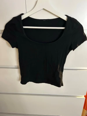 Svart croppad topp med kort ärm - Säljer en  svart croppad topp med rundad urringning och korta ärmar. Saknar lappen men märket är H&M Divided.