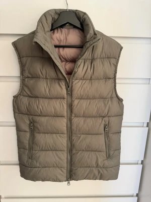 Lexington Väst storlek s - Säljer denna dunväst från Lexington i storlek S. Västen har quiltad design, hög krage och dragkedja framtill samt två fickor med dragkedja. Perfekt att slänga över en hoodie eller tröja för extra värme.