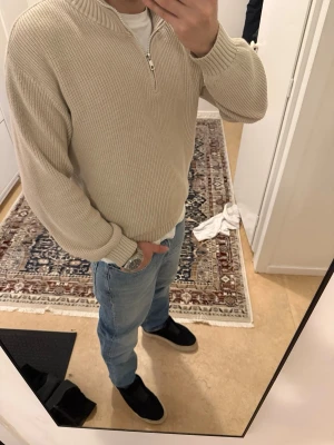 Beige stickad half zip-tröja Kappahl - Snygg beige stickad tröja från Kappahl med half zip-dragkedja och hög krage. Tröjan har ribbade muddar och är långärmad. 