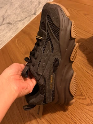 Bruna mesh chunky sneakers från Steve Madden - Chunky sneakers från Steve Madden i brun mocka och mesh med grov brun sula. Snygga detaljer med snörning och guldfärgad logga på sidan. Platt sula och rund tå ger en cool streetstil. Perfekta för dig som gillar trendiga och bekväma skor.