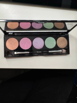 Isadora ögonskuggspalett pastell - Snygg ögonskuggspalett från Isadora med fem skimriga nyanser: koppar, rosa, lila, mintgrön och brons. Kommer i en svart plastförpackning med spegel och dubbeländad borste. Perfekt för kreativa och färgglada ögonlooks.