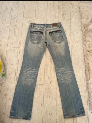 Blå bootcut jeans med broderade fickor - Midjemått: 39cm innerbenslängd: 84cm. De har ett litet hål som syns på sista bilden💕