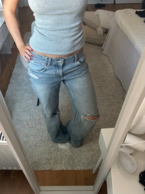 Ljusblå jeans med hål - Jeans med hål från Zara. Storlek 34. De är utsydda i benet så att de passar mer som bootcut/wide istället för rakare passform. De är även uppsydda och passar bra (rätt långa i benen) för mig som är 163 cm. Helt slutsålda i storleken på Zaras hemsida. 