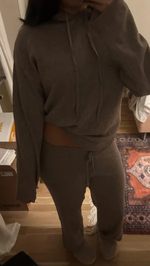 Stickat set - Säljer en beige hoodie som är i S med tillhörande byxor i M. mjuk stickad kvalitet med huva och snörning. Matchar snyggt med de låg midjade byxor i samma material för en avslappnad look.