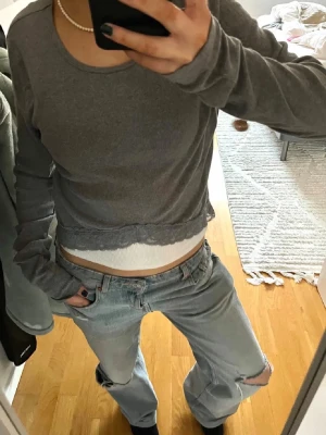 Grå långärmad tröja med spets från Hollister - Supersöt grå långärmad tröja från Hollister med rund hals, ribbad struktur och spetsdetalj längs nederkanten. Storlek L men väldigt liten i modellen (har vanligtvis xs/s)