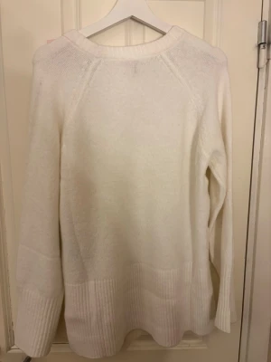 Vit stickad tröja från Nelly - Vit stickad tröja från Nelly i storlek XS. Tröjan har rund hals, långa ärmar och breda ribbade muddar vid nederkant och ärmslut. Mjuk och skön, perfekt för kyliga dagar. Enkel och stilren design som är lätt att matcha. Helt oanvänd bara testat en gång!