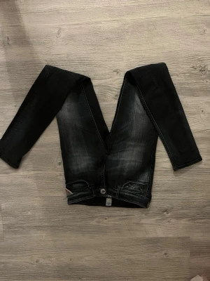 Replay skinny jeans svart/grå - Säljer ett par Replay skinny jeans i svart/grå tvätt med snygga slitningar. Klassisk femficksmodell med Replay-logga på fickan och metallknapp framtill. Jeansen har smal passform och är tillverkade i stretchigt jeanstyg för extra komfort.