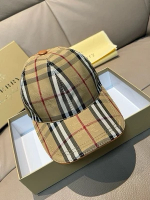 Rutig Burberry keps i beige - Säljer en klassisk Burberry keps i beige med det ikoniska rutiga mönstret i svart, vitt och rött. Kepsen har justerbart spänne bak i brunt läder med präglad Burberry-logga. Perfekt accessoar för en trendig och tidlös look.