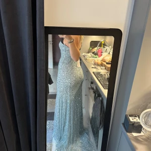 Glittrig blå långklänning med paljetter - Säljer en blå långklänning från märket Beauut, täckt med glittriga paljetter. Klänningen har v-ringad urringning, smala axelband och figurnära passform. Perfekt för bal