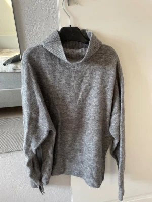 Grå polotröja från BikBok - Mysig grå polotröja från BikBok. Tröjan har lång ärm, ribbade muddar och en hög polokrage. Perfekt för kyliga dagar och enkel att styla till jeans eller kjol<3