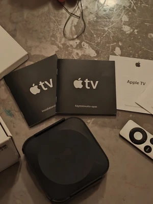 Apple TV (Model A1469) - Apple TV (Model A1469) med fjärrkontroll och originalmanualer. Stöd för 1080p HD, HDMI och 802.11n Wi-Fi. Enheten och tillbehör ser ut att vara i gott skick, inga synliga defekter eller större slitage. Perfekt för streaming av filmer, serier och musik.