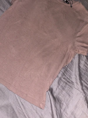 Brun ribbad t-shirt från Bik Bok - En basic brun t-shirt från Bik Bok i storlek XL. T-shirten är ribbad och har korta ärmar samt rund halsringning. Perfekt för en enkel och avslappnad stil.