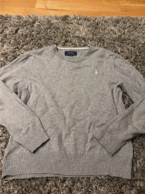 Grå tröja från Polo Ralph Lauren - Säljer en stilren grå tröja från Polo Ralph Lauren i mjuk pima bomull. Klassisk rund halsringning, diskret broderad logga på bröstet och ribbade muddar vid ärmslut och nederkant. Pris Kan diskuteras 🤍💕