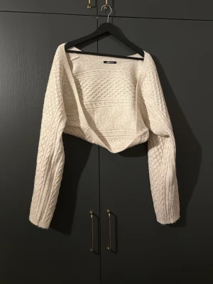 Beige croppad stickad tröja Gina Tricot - Säljer en beige bolero från Gina Tricot. Boleron har ett snyggt kabelstickat mönster och långa ärmar. Supermysig och trendig modell! Säljs inte längre och är använd endast en gång!