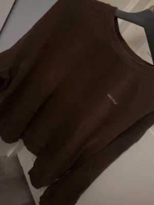 Brun sweatshirt från H&M - Mysig brun sweatshirt från H&M med diskret broderad text på bröstet. Tröjan har rund halsringning och långa ärmar, perfekt för chill dagar. Tillverkad i mjuk bomull för maximal komfort.