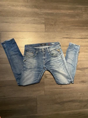 Replay Anbass jeans - Säljer ett par Replay Anbass jeans i blå tvätt med slitningar och snygga detaljer. Klassisk  Replay-logga på fickan som ger extra edge. Jeansen har normal passform och är tillverkade i mjukt bomullsmaterial för skön känsla. Jeansen har fabrikslitningar vilket är väldigt eftertraktat. Mycket bra skick!