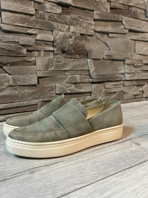 Gröna mockaloafers från Vagabond - Snygga loafers från Vagabond i grön mocka med vit platåsula. Skorna har en stilren design med rund tå och bred rem över foten. Ovandelen är i skinn och insidan har textilfoder. Perfekta för dig som gillar en clean och modern look.