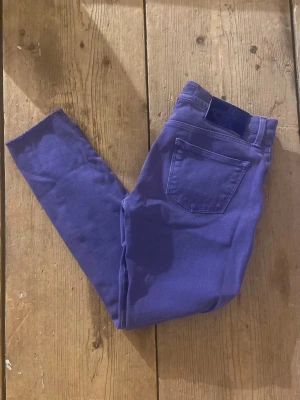 Lila  jeans från Jacob Cohën - Säljer ett par lila skinny jeans från Jacob Cohën i storlek 28. Byxorna har klassisk femficksdesign, bälteshällor och råa kanter vid benslut. Materialet är mjukt och stretchigt, vilket gör dem riktigt bekväma att bära. Jenas en har blivit avklippta vid botten, såklart från fabrik
