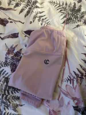 Ljusrosa leggings från ICONIC  - Säljer ett par ljusrosa leggings från ICONIC . De har en hög midja och är tillverkade i ett stretchigt syntetmaterial som passar perfekt till träning. Diskret logga på låret och smal passform som sitter snyggt längs benen. Är använd bara 1 gång. 