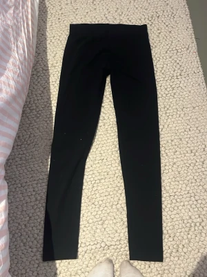 Svarta leggings med hög midja - Säljer ett par svarta leggings med hög midja. De är tighta och har en enkel, stilren design utan synliga detaljer. Perfekta att matcha med oversized tröjor eller hoodies för en chill look. 134-140 i storlek 