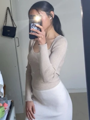 Beige ribbad långärmad topp - Säljer en beige ribbad topp med lång ärm och snygg v-ringad hals. Toppen har en figurnära passform och är tillverkad i ett stickat material som känns mjukt mot huden. Perfekt att styla med jeans eller kjol för en trendig look.