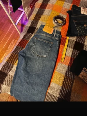 Acne Studios Blå Konst Jeans - Säljer ett par klassiska blå jeans från Acne Studios Blå Konst. Modellen har raka ben, normal passform och traditionell femficksdesign. Jeansen är tillverkade i bomull och har en snygg tvättad blå färg med subtila slitningar framtill. Pris förhandlingsbart och hör av er vid frågor!