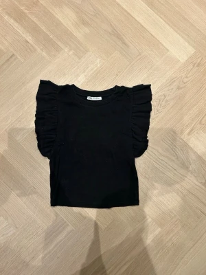 Svart volangärmad topp från Zara - Säljer denna jättegulliga Zara topp på grund av ingen användning, den är i st M men skulle säga att alla st är typ samma. Den är även använd ett fåtal gånger. Skriv om ni vill ha bilder på💕