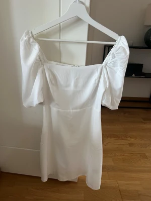 Vit klänning från Nelly  - Supersöt vit kortklänning med puffärmar och rak urringning. Klänningen är bara använd en gång och är där med i väldigt bra skick 🥰