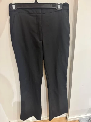 Svarta kostymbyxor från Zara, S - Klassiska svarta kostymbyxor från Zara i storlek S. Byxorna har raka ben, hög midja och stängs med hake och dragkedja. Snygga fickor både fram och bak. Materialet är mjukt och följsamt, perfekt till en clean och stilren look.
