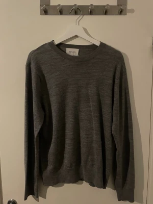 Grå stickad tröja från Sandö - Mysig grå stickad tröja från Sandö i storlek M. Tröjan har rund halsringning och långa ärmar, perfekt för kyligare dagar. Enkel och stilren design som passar till det mesta.