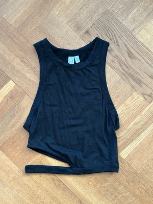 Svart croppad linnetopp - Säljer en svart croppad linnetopp. Toppen är ärmlös i mjuk bomull och har en extra detalj. Perfekt till sommaren!