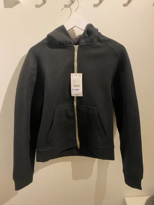 Svart hoodie med dragkedja  - Jag säljer en helt ny snygg svart hoodie med dragkedja. Jag säljer den då den är för liten för mig. Lappen sitter kvar. Pris kan diskuteras.