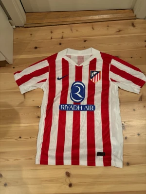 Atletico Madrid matchtröja röd/vit - Säljer en Atletico Madrid matchtröja med röda och vita vertikala ränder🙋Tillverkad i lätt polyester med Dri-FIT-teknologi för bra andning.😮‍💨Inprincip helt oanvänd bara testat den. Prislappen finns inte kvar🚨 Den är i storlek S! Vid frågor hör av dig‼️